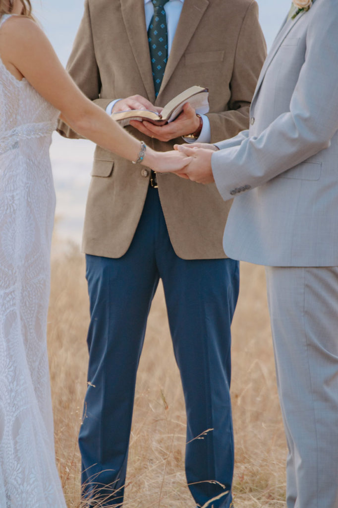 Vanessa and Camden Hold Hands During Wyoming Wedding Ceremony