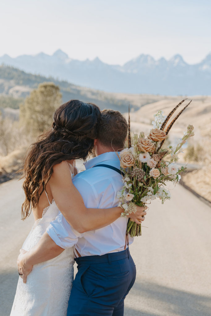 Couple looks off into the tetons after wedding
