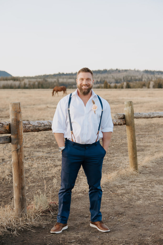 groom standin in front of horses and tetons in Jackson Hole, Wyoming
