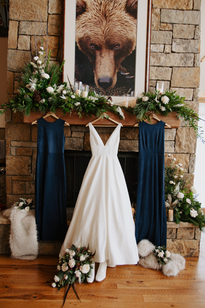 Bride's dress and bride-maids dresses hanging on a rustic mantle