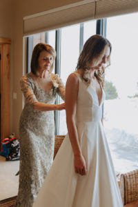 Mother of the bride helping the bride by adjusting her dress