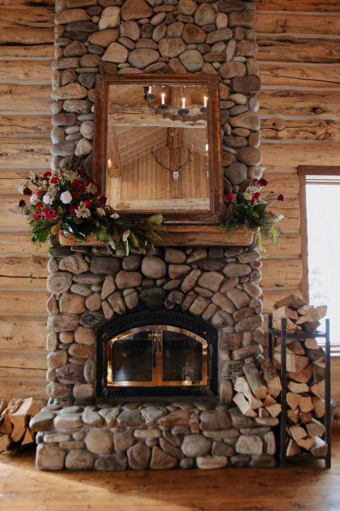 Wedding flowers cascade across a stone fireplace at Bentwood Inn in Jackson Hole for a winter wedding