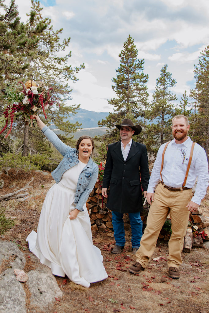 Mountain top wedding in Wyoming with couple cheering and bride tossing bouquet