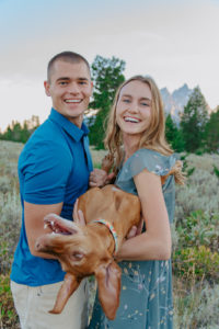 Ariane & Jackson candid engagement photo with their dog in a gorgeous field
