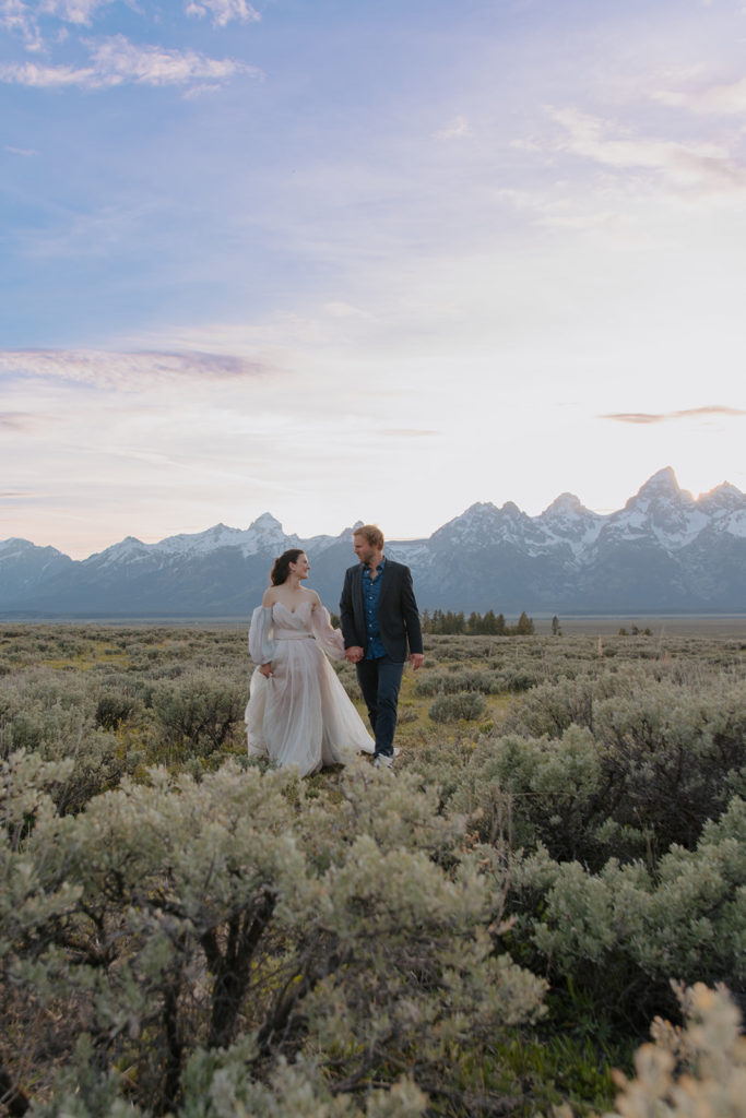 After getting married in Jackson Hole a couple walks in sage field