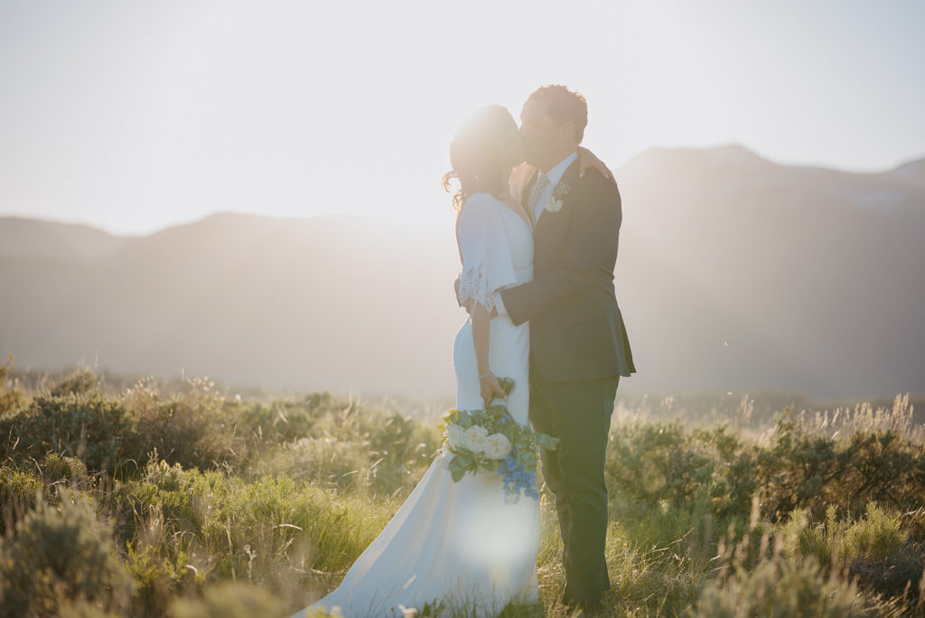Couple kisses in front of Tetons after their wedding in Jackson Hole at Spring Creek Ranch