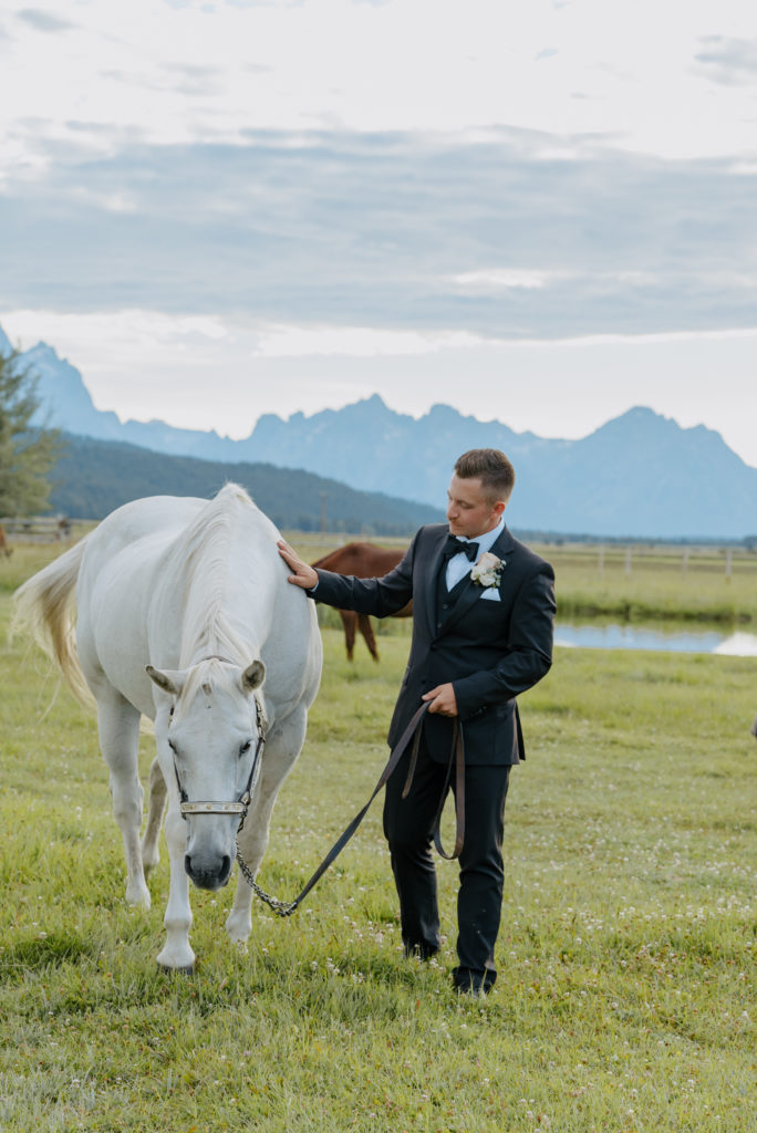 Groom posing with white horse at Diamond Cross ranch. 