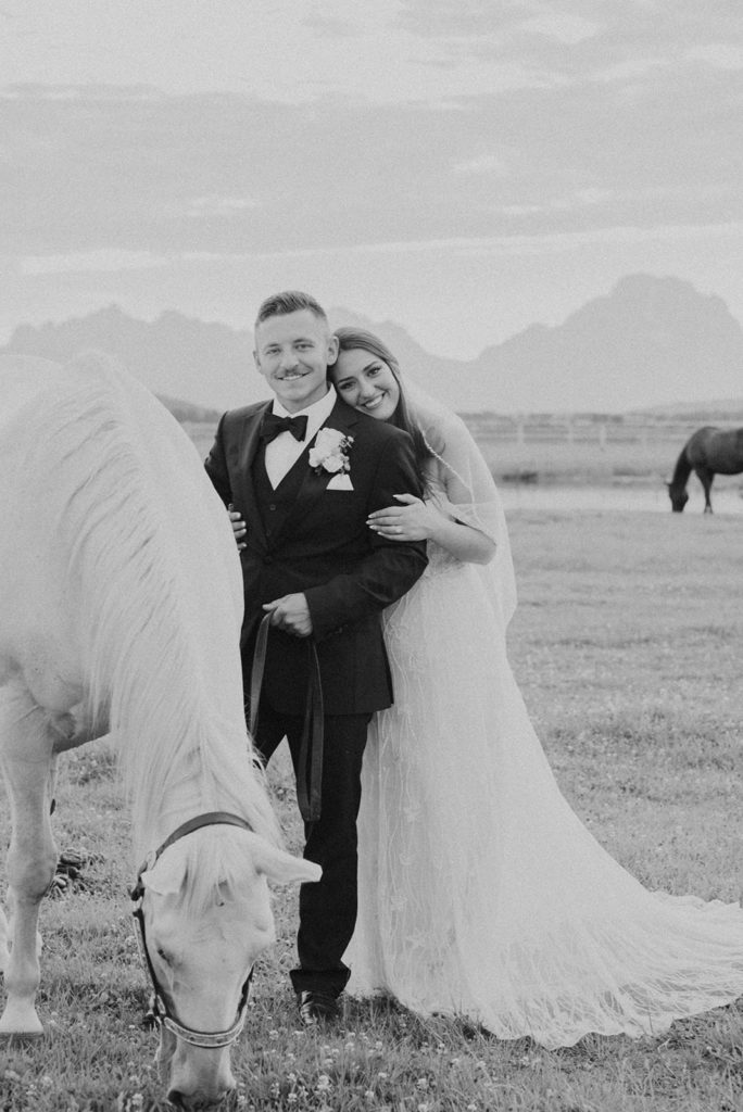 Black and white photo of bride and groom with white horse at Diamond Cross ranch. 