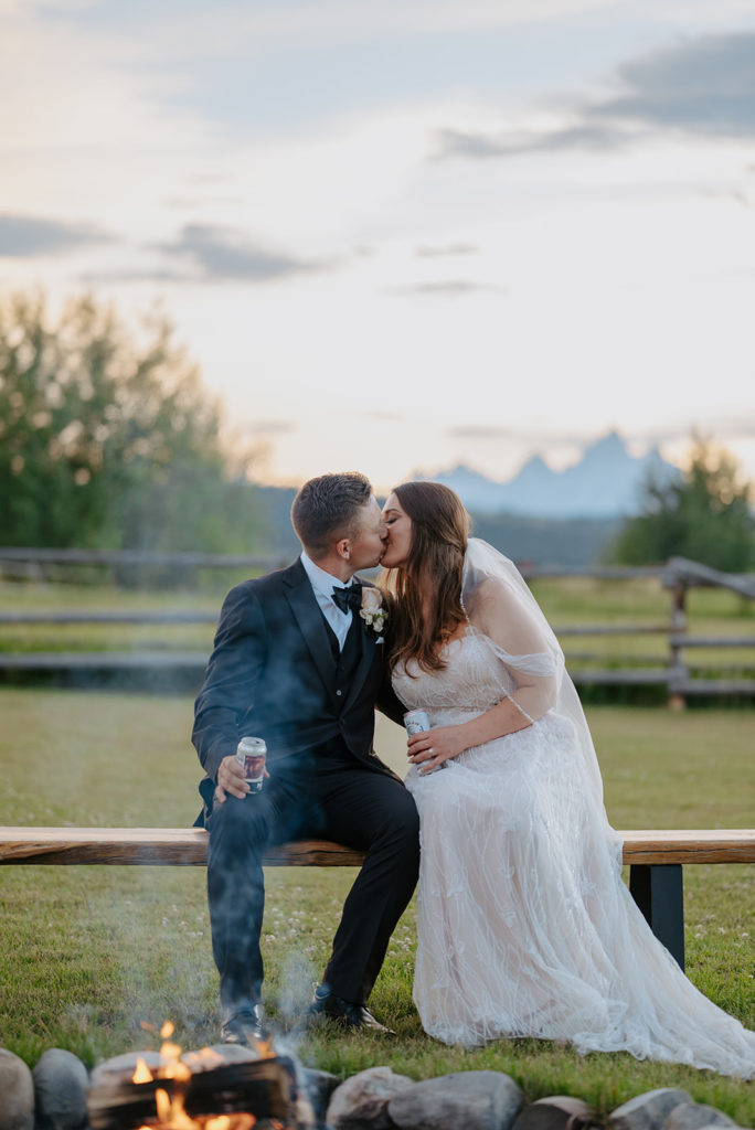 Bride and groom kissing in front of fire pit at Diamond Cross ranch. 