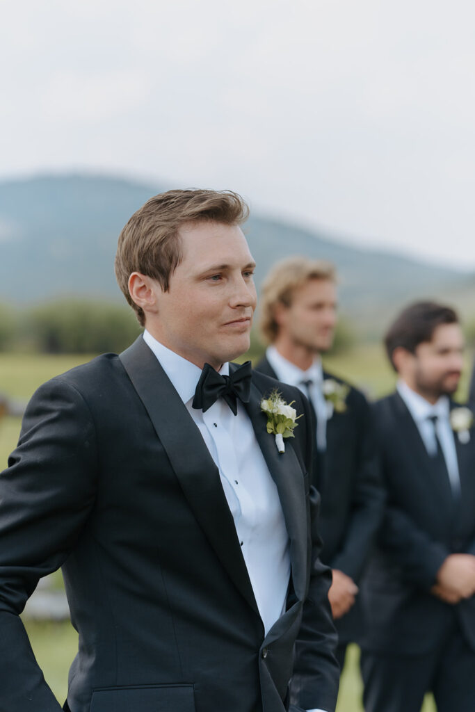 Groom looks at bride during wedding as she walks down the aisle at Diamond Cross Ranch